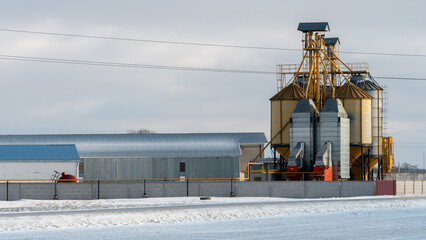 Silver silos against the blue sky in winter. Grain storage in winter at low temperatures. Production for processing, drying, cleaning and storage of agricultural products, flour, cereals and grain