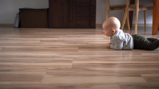 An infant crawls across the room in front of the camera
