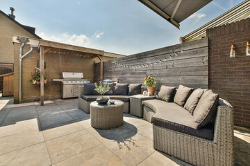 Neat powerful patio with sitting area and small garden near wooden fence - obrazy, fototapety, plakaty