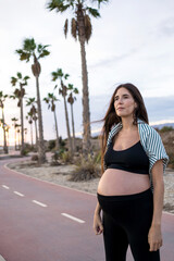 pregnant young woman in sportswear smiling relaxes outdoors