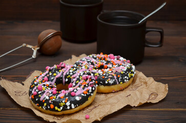Obraz na płótnie Canvas two donuts and cups with coffee on a wooden background