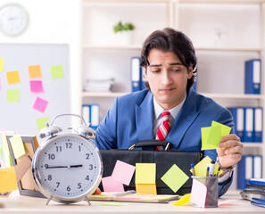 Young male handsome employee in conflicting priorities concept
