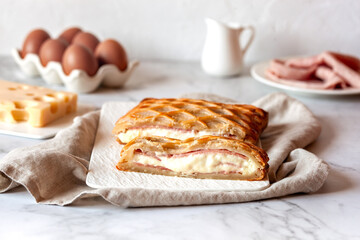 Puff with ham and cheese cut on a rectangular plate on a kitchen table