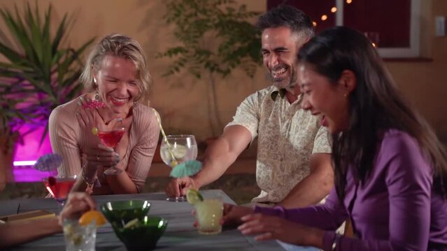 Cheerful friends drinking cocktails. People having fun summer night. Lifestyle and nightlife concept.