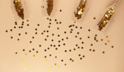 Champagne glasses filled with gold star shaped sequins, flat lay