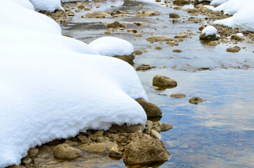 Snow melts and a crystal clear river shows its calm face
