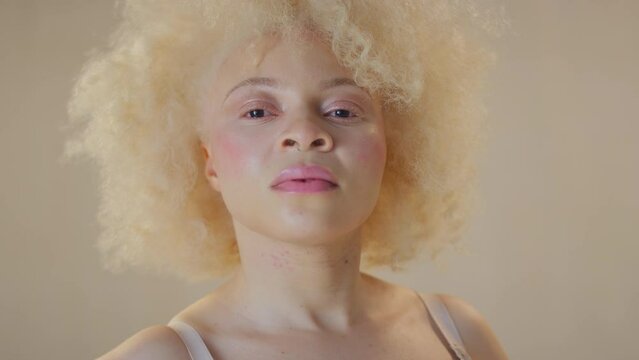 Studio shot of confident and positive young albino woman smiling and looking through cardboard picture frame - shot in slow motion