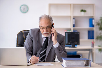 Fototapeta premium Old male employee working in the office