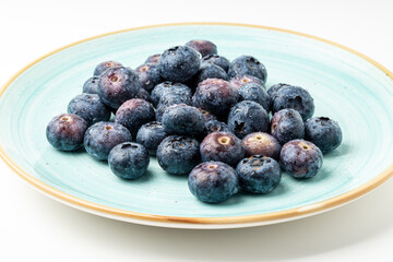 Plate full of blueberries on white background