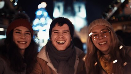 Three happy friends with sparklers on new year's eve in the middle of the street in the lights of the Christmas Tree. Concept for Christmas, New Year, Eve, Celebration, Friends, Family, Sparklers. - Powered by Adobe
