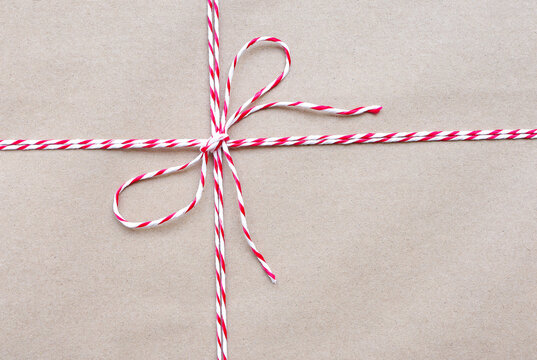 Top view photo of String or tied in bow on brown paper packaging. white and red Christmas wrapping ropes tied in bow for gift box.