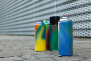 Used cans of spray paints on pavement, closeup. Space for text