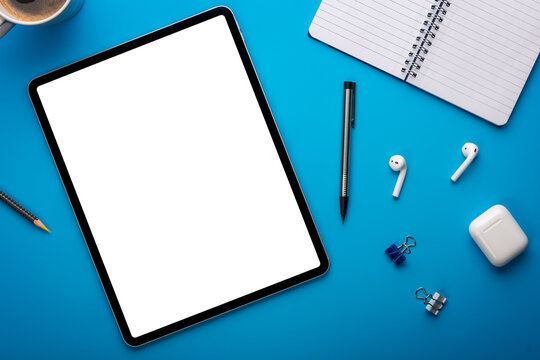 Notebook and Tablet Computer on Blue Desk or background laying flat on Creative workplace as mockup or Template with empty or blank page or screen