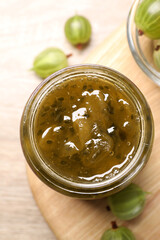 Jar of delicious gooseberry jam and fresh berries, flat lay