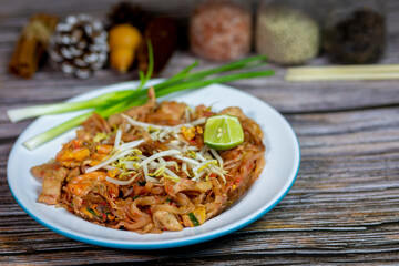 Pad Thai with shrimp and tofu, served on the left side of the table and seasonings.