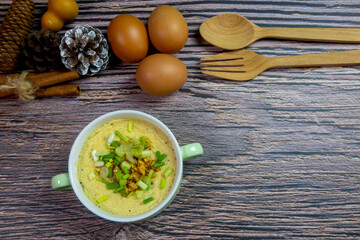 It's very cold this morning i cooking steamed eggs hot sprinkle with spring onions and fried garlic serve on the wooden table is it breakfast give warmth to the body useful and good for healthy.