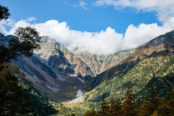 Beautiful background of the center of Kamikochi national park by snow mountains, rocks, and Azusa rivers from hills covered with leaf change color during the Fall Foliage season.