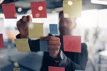 Close up of businessman is glues sticky notes on motivation board in modern office