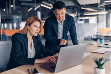 Two multiethnic coworkers working together analyzing the charts in office 