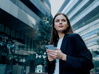 Portrait of a stylish young businesswoman in a jacket with a phone in her hands, online shopping, lifestyle in the pace of the big city