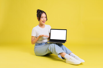 Naklejka premium portrait of a beautiful young asian girl sitting on a yellow background