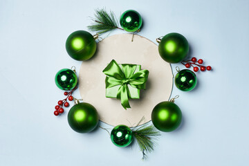 some green christmas ornaments on a white surface with red berries and pine cones around the frame, as well for decoration