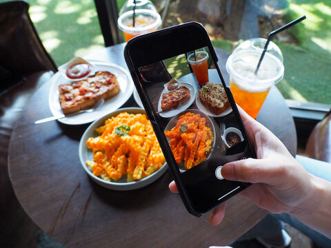 Girl's Hand Use Your Cell Phone To Take Food On The Table.