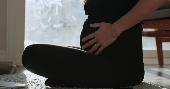 Pregnant woman rubbing second trimester belly - side profile