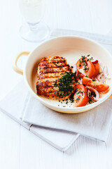 Grilled Turkey Breast with tomato salad. Bright wooden background. Copy space.
