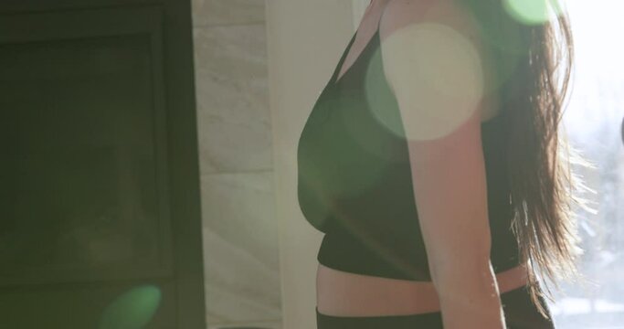 Second trimester pregnant woman does over the shoulder stretches in morning sunlight