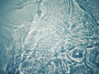 Defocus blurred transparent blue colored clear calm water surface texture with splashes and bubbles. Trendy abstract nature background. Water waves in sunlight with copy space. Blue watercolor shining