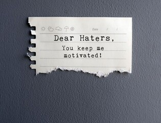 Yellow Note on grey wall with text THANK YOU HATERS , FOR BEING MY MOTIVATORS - Self reminder to...
