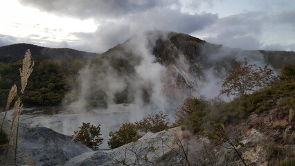 Fototapeta na wymiar Noboribetsu Onsen Picnic Site, Japan. Hot spring with steam and mountain.