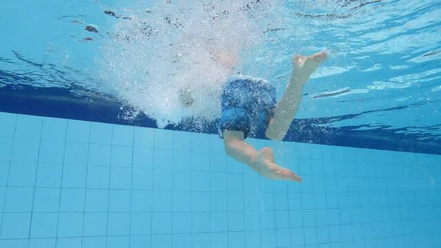 Young boy swimming in pool - underwater shot looking up