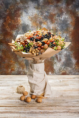 Gift bouquet of natural nuts and dried fruits. Ideas for original handmade gifts. Sweet healty nutrition. Rustic background. Vertical shot. Copy space