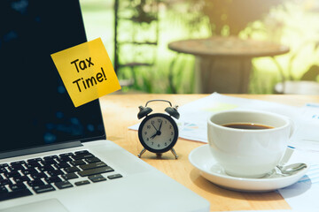 Tax time Concept. tax time post-it on a laptop and clock, a cup of coffee, and an Individual income tax return form . income tax online - obrazy, fototapety, plakaty