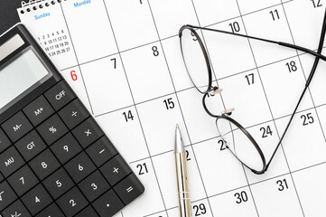 Calculator with glasses and pen on calendar. Business concept. Deadline of tax payments.
