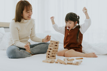 Mom and little 4 years old kid daughter playing education wooden box puzzle toy together at living...