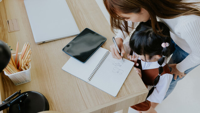 Young asian mother teaching holding little kid girl daughter hand writing drawing book, Education learning concept at home