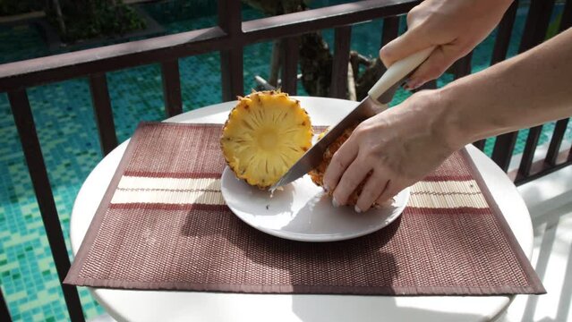 A girl's hand cuts a pineapple