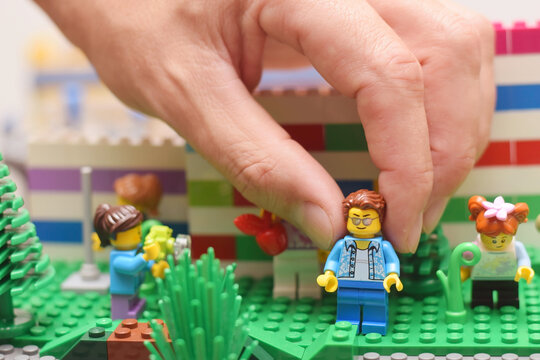 A man is playing with lego minifigure. Editorial illustrative image of popular toy brand with plastic bricks.
