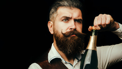 Portrait of a bearded waiter holding a champagne bottle. Close up portrait of man uncorking a...