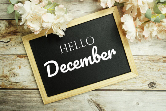 Welcome December text message on blackboard with flower decoration on wooden background
