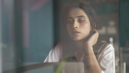 Feeling tired and stressed. Young Indian woman sitting looking deep in thought exhausted and tired during working at coffee shop using laptop.Asian girl with a laptop problems with the project. - Powered by Adobe