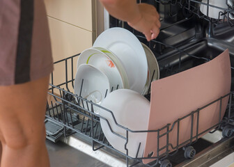 a woman loads dirty dishes into the dishwasher