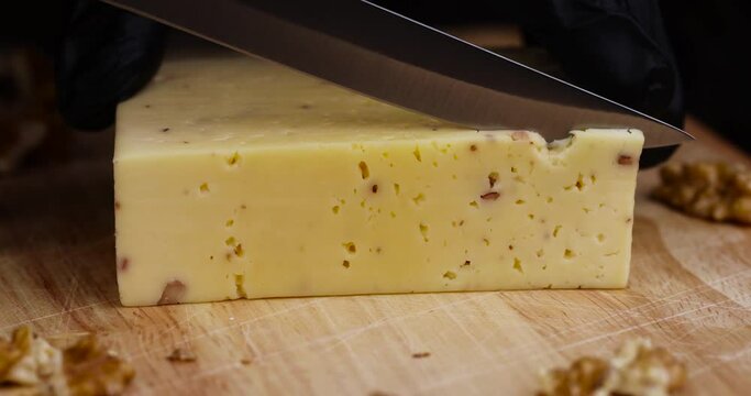 Cut into pieces ripe hard cheese with walnuts, cutting into slices of cheese with nuts