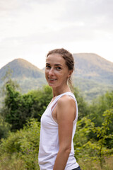 Smiling young woman in the forest against the backdrop of mountains