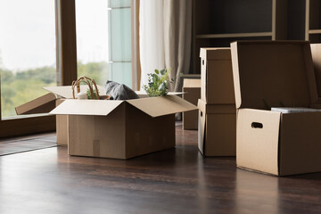 Big cardboard boxes with packed personal stuff stacked on floor in living room on relocation or...