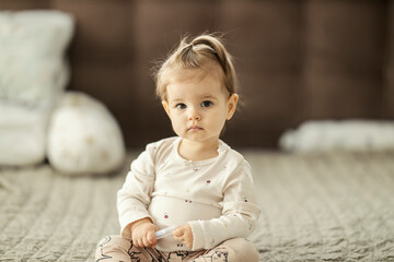 Portrait of a cute little girl sitting on the beg and looking at the camera.