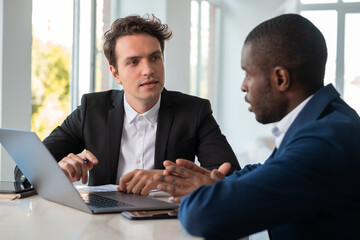 Serious African American businessman wearing formal suit talking to colleague